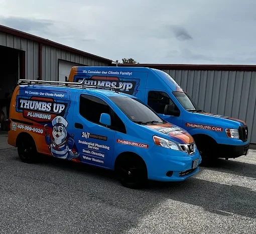 Two blue Thumbs Up Plumbing service vans parked outside